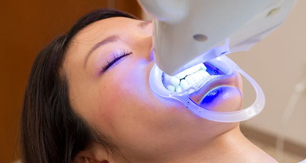 레이저 장비로 치아 미백 시술을 받는 여성 환자 / Female patient receiving laser teeth whitening treatment at dental clinic